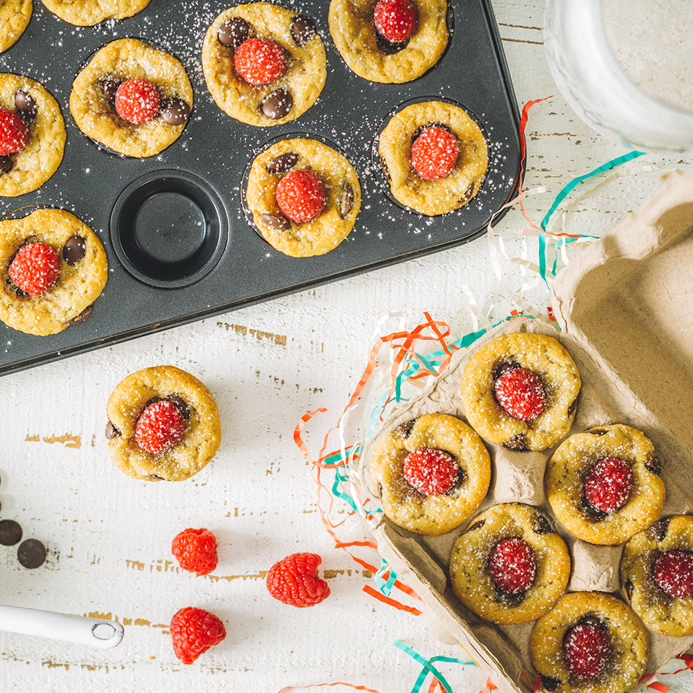 Chocolate chip cookies topped with raspberries and powdered sugar