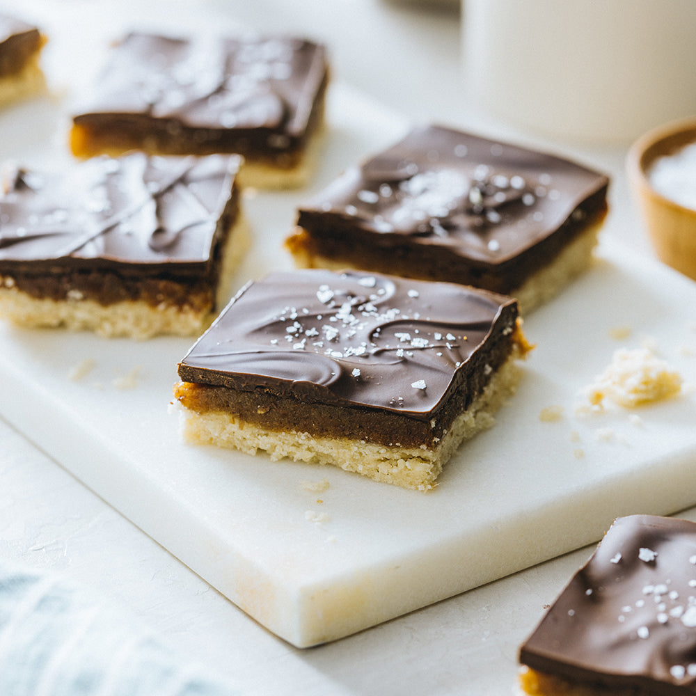 Chocolate Caramel Shortbread Bars on a White Cutting Board
