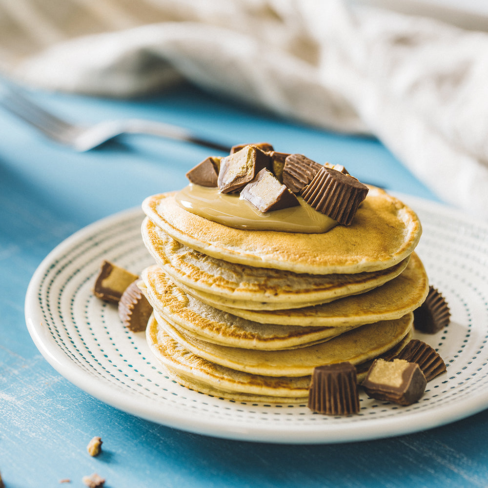 A Stack of Sunflower Butter Cup Pancakes Topped With Sunflower Butter and Chopped Sun Cups