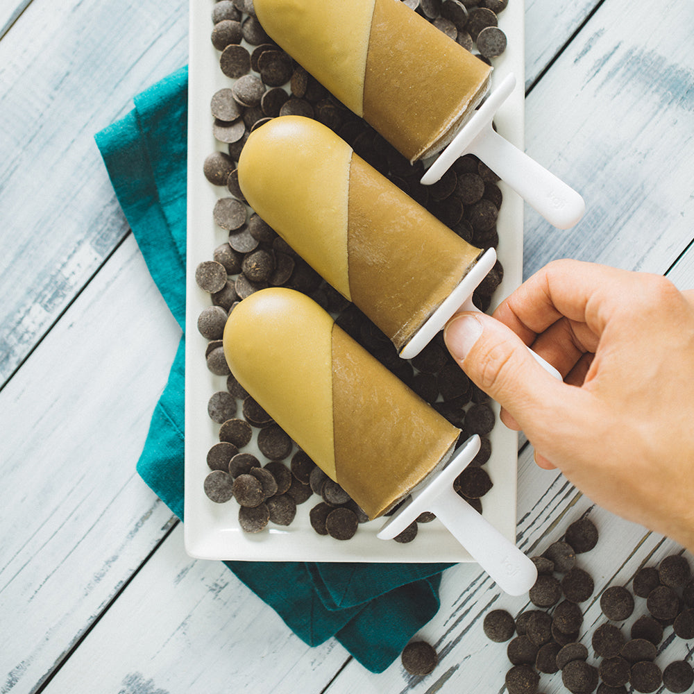 Person grabbing sunbutter popsicle in a bed of chocolate chips