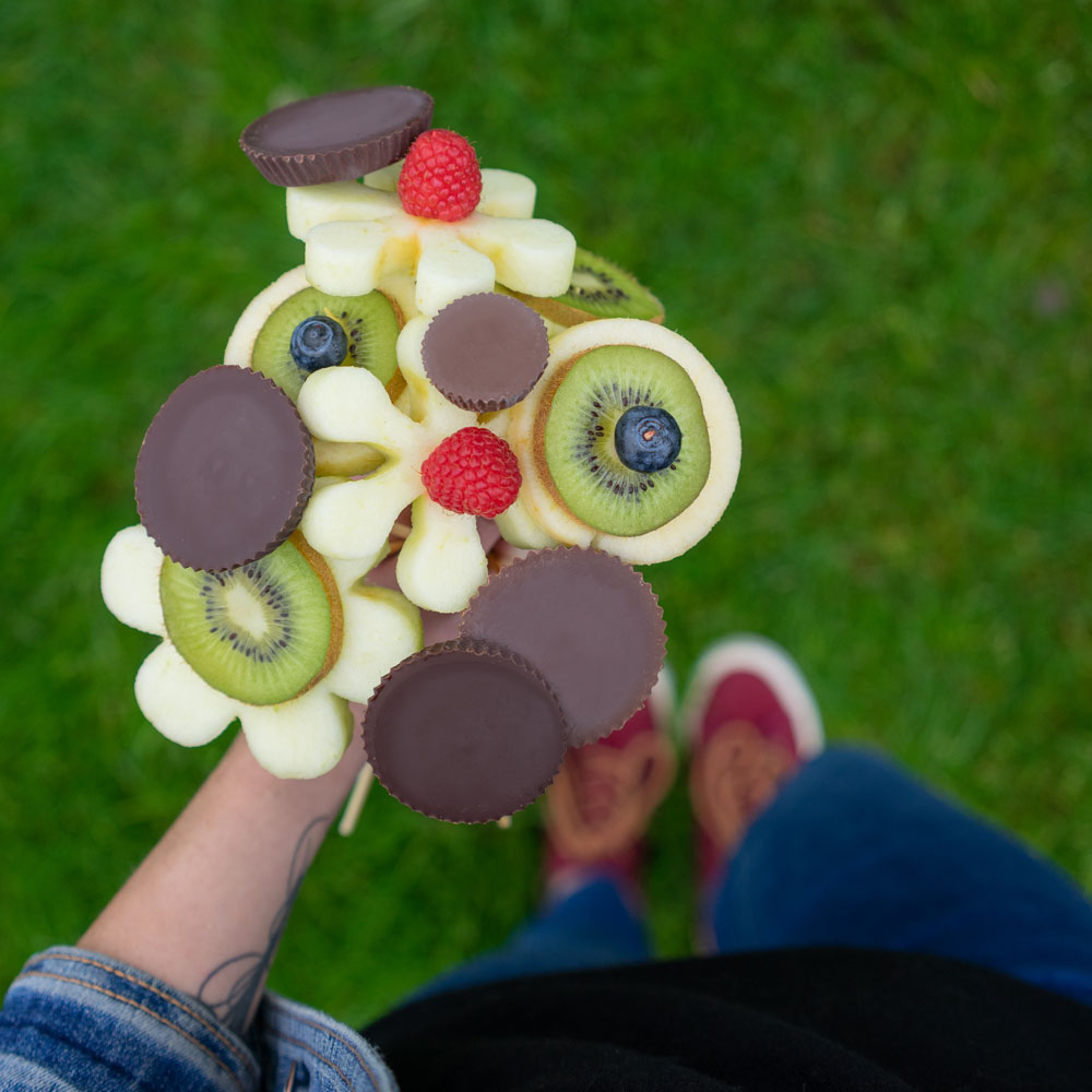 Person holds bouquet made of fruit and Sun Cups made to look like flowers 