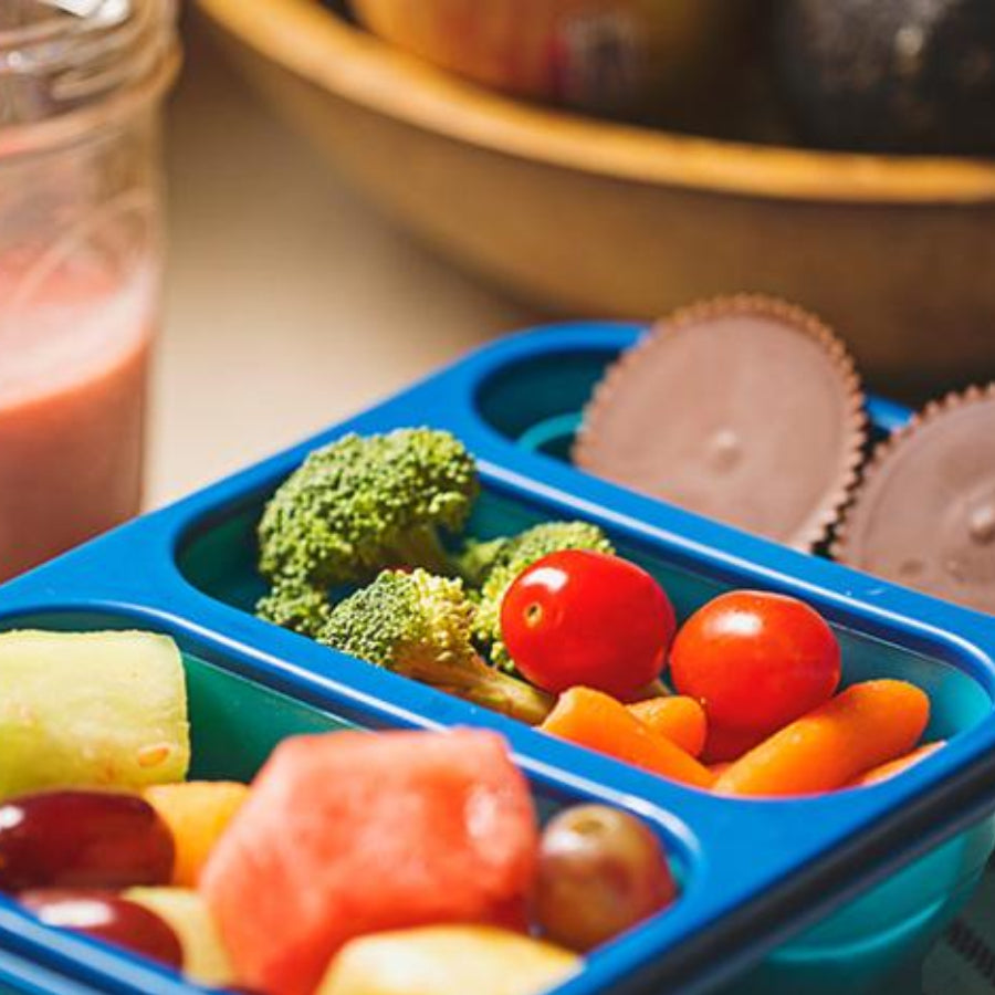 Blue Lunchbox Filled With Fruit, Fresh Veggies and Chocolate Sun Cups